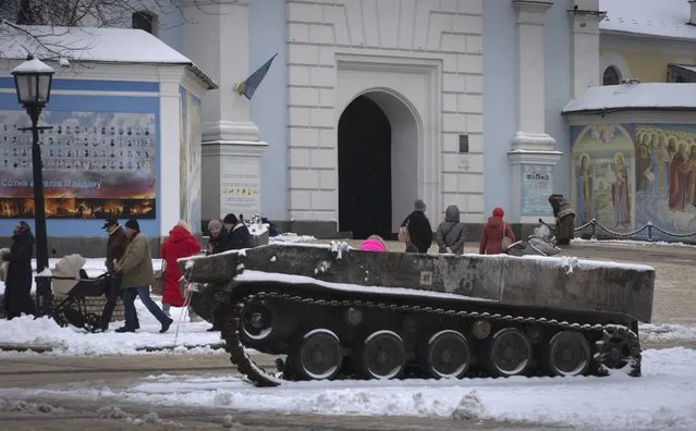 People pass by the entrance to St.Michael Cathedral, with a damaged Russian military vehicle in the foreground, in central Kyiv, Ukraine, Monday, December 12, 2022. Ukraine has been fighting with the Russian invaders since Feb. 24 for over nine months. (Photo by Efrem Lukatsky/AP Photo)