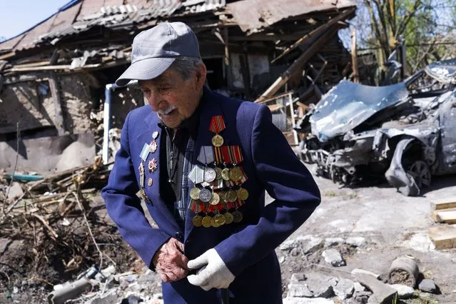 War World II veteran, Ivan Lisun, 97, wears a jacket with his medals and pins outside his house which was damaged after a Russian bombing, amid Russia's attack on Ukraine, in Zolochiv near Kharkiv, Ukraine on May 6, 2022. (Photo by Ricardo Moraes/Reuters)