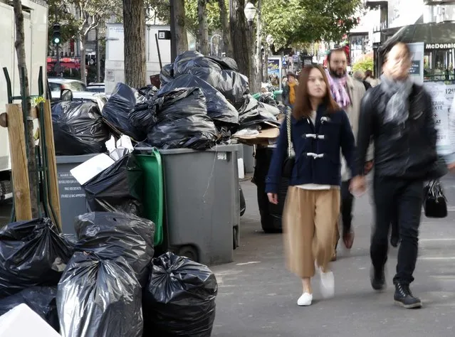 People walk past bins that overflow with bags of garbage during a strike by rubbish collectors in Paris, France, October 7, 2015. Garbage bins accumulate along sidewalks as half of the districts in the French capital are affected by the strike which started on Monday. (Photo by Jacky Naegelen/Reuters)