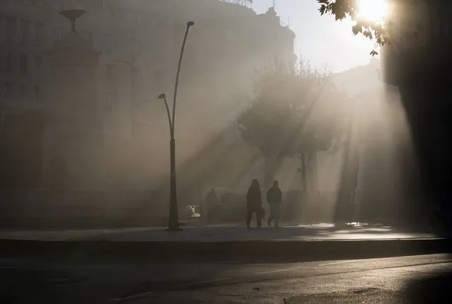 People walk in the street amid dense fog at morning at Terazije square in downtown Belgrade, Serbia, Wednesday, November 9, 2022. (Photo by Darko Vojinovic/AP Photo)
