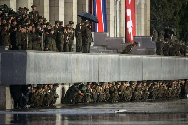 North Korean soldiers shelter from the rain beneath a balcony following a mass military parade in Pyongyang on October 10, 2015. (Photo by Ed Jones/AFP Photo)