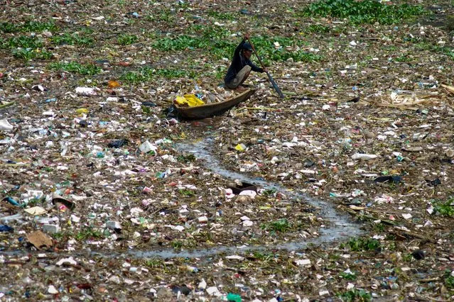 A man collects plastic from the polluted Citarum river in West Bandung on December 14, 2022. (Photo by Timur Matahari/AFP Photo)