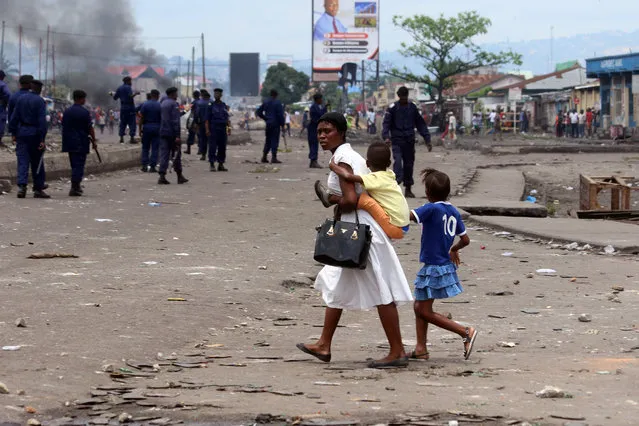 A family pass near Congolese riot police during a protest in Kinshasa, Democratic Republic of Congo, Monday, September 19, 2016. (Photo by John Bompengo/AP Photo)