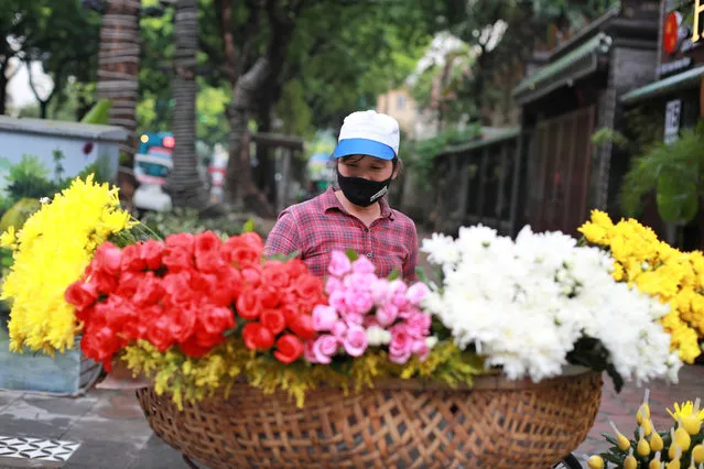 A flower vender wearing a face mask to protect against the coronavirus waits for customers in Hanoi, Vietnam, Monday, August 3, 2020. Vietnam has tightened travel and social restrictions after the country's death toll of COVID-19 to six. (Photo by Hau Dinh/AP Photo)