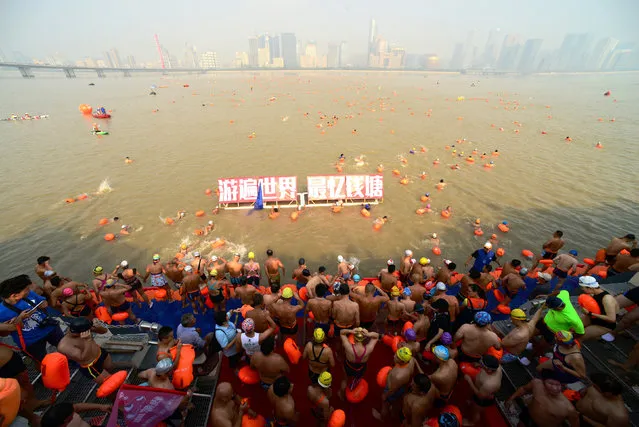 Participants take part in a local swimming event across the Qiantang River in Hangzhou, Zhejiang Province, China, September 24, 2016. The red Chinese characters read: “Swim around the world, and the most rememberable is Qiantang”. (Photo by Reuters/Stringer)