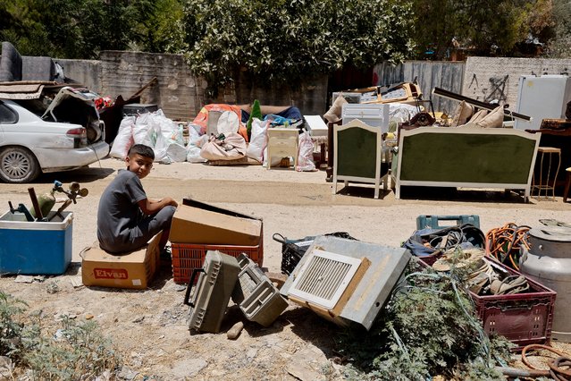 A boy sits next to belongings as Palestinians remove them from their homes threatened with demolition, during the ongoing Israeli military operation in Tulkarm camp, in the Israeli-occupied West Bank on July 2, 2025. (Photo by Raneen Sawafta/Reuters)