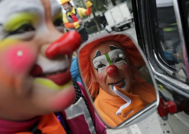 A clown is reflected on a side mirror of his car while speaking to another clown before they take part in a photo session at the Monument to the Revolution during the Latin American Clown Convention in Mexico City, Mexico, October 21, 2015. (Photo by Henry Romero/Reuters)