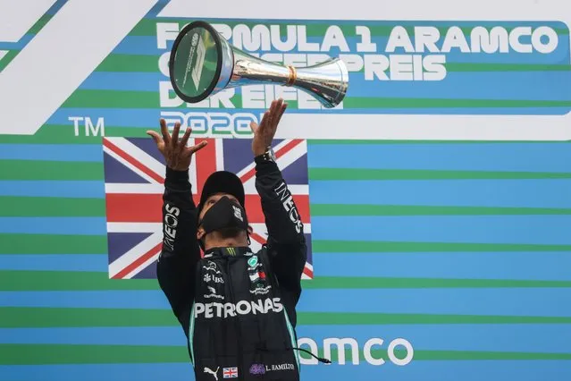 Mercedes driver Lewis Hamilton of Britain throws the trophy in the air at the podium as he celebrates after winning the Eifel Formula One Grand Prix at the Nuerburgring racetrack in Nuerburg, Germany, Sunday, October 11, 2020. Hamilton with this win equals 91 wins in F1 races as F1 legend Michael Schumacher. Red Bull driver Max Verstappen of the Netherlands finished second and Renault driver Daniel Ricciardo of Australia finished third. (Photo by Ronald Wittek/Pool via AP Photo)