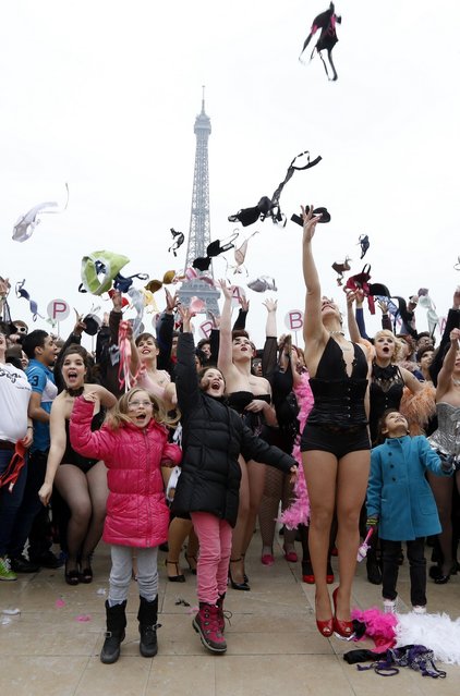 Woman throws bras on March 25, 2013 at the esplanade des droits de l'homme, in front of the Eiffel tower in Paris, during a happening called by “Pink Bra Bazzar”, a French organization fighting against and sensitizing on breast cancer. (Photo by Pierre Verdy/AFP Photo)