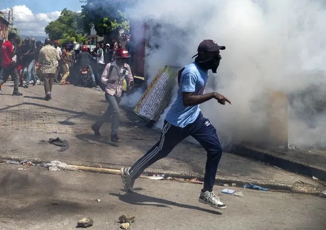 Protesters run from tear gas launched by police to disperse protesters demanding the resignation of President Jovenel Moise in Port-au-Prince, Haiti, Saturday, October 17, 2020. (Photo by Dieu Nalio Chery/AP Photo)