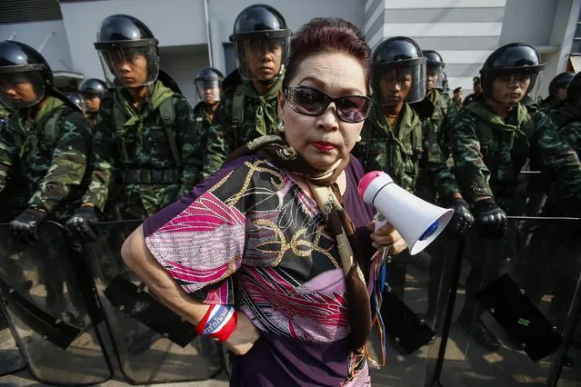 An anti-government protester stands near Thai soldiers guarding a Defence Ministry compound, which is serving as a temporary office for Thai Prime Minister Yingluck Shinawatra, in north Bangkok, in this February 19, 2014 file photo. (Photo by Athit Perawongmetha/Reuters)