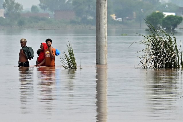 Residents wade through a flooded area of Kartarpur, a town in Punjab province, on August 28, 2025. (Photo by Arif Ali/AFP Photo)