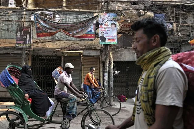 A cycle rickshaw puller pedals with a passenger in the old quarters of Dhaka, Bangladesh, Monday, March 13, 2023. (Photo by Aijaz Rahi/AP Photo)