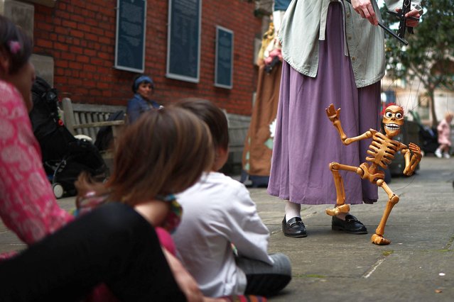 People watch a marionette performance during the Covent Garden's May Fayre & Puppet Festival, at Covent Garden, central London, on May 12, 2024. (Photo by Henry Nicholls/AFP Photo)