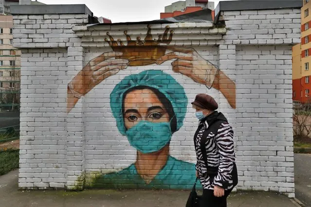 A woman wearing a protective face mask walks past coronavirus – themed graffiti depicting a medic in Bugry, outside St. Petersburg, Russia, 17 November 2020. In the past 24 hours, Russia registered 22,410 new cases caused by the SARS-CoV-2 coronavirus infection and a total of 442 coronavirus-related deaths. (Photo by Anatoly Maltsev/EPA/EFE)