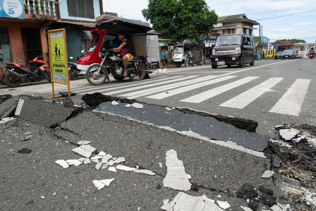Vehicles maneuver past a damaged part of a road in Bogo City on October 1, 2025, after a powerful 6.9 magnitude earthquake jolted the central Philippines, killing dozens on the island of Cebu with fears the toll could rise. The death toll from a powerful earthquake in the central Philippines approached 60 on October 1, with injured patients overwhelming hospitals on the island of Cebu as workers carried dozens of body bags away in the chaotic aftermath. (Photo by Ted Aljibe/AFP Photo)