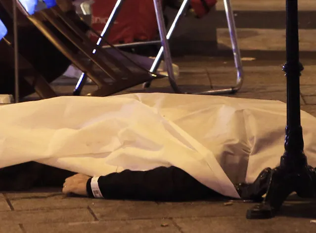  A victim is pictured on the pavement outside a Paris restaurant, Friday, November 13, 2015. (Photo by Thibault Camus/AP Photo)