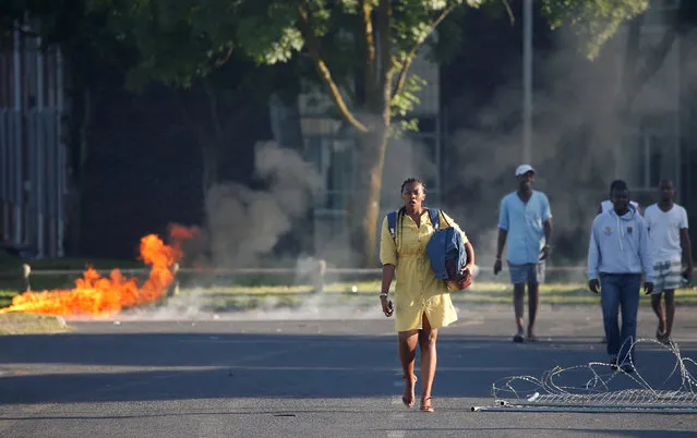 Students walk past a burning barricade as clashes between students and police erupt at the University of the Western Cape during protests demanding free tertiary education in Cape Town, South Africa, October 19, 2016. (Photo by Mike Hutchings/Reuters)