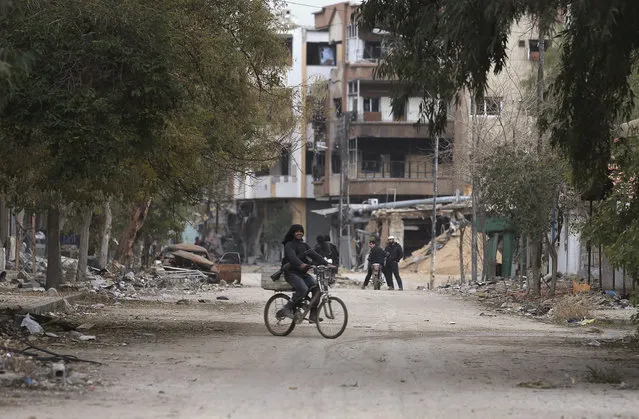 A rebel fighter carrying his weapon rides a bicycle along a street in Jobar, a suburb of Damascus, December 22, 2014. (Photo by Bassam Khabieh/Reuters)