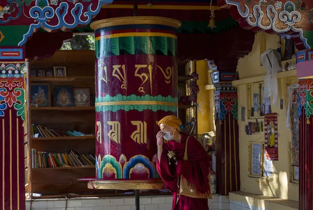 An exile Tibetan Buddhist monk wearing a mask as precaution against the coronavirus rotates a prayer wheel in Dharmsala, India, Friday, December 18, 2020. (Photo by Ashwini Bhatia/AP Photo)