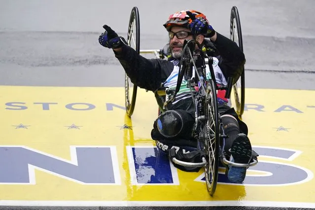 Boston Marathon bombing survivor Marc Fucarile points to spectators while crossing the finish line of the Boston Marathon, Monday, April 17, 2023, in Boston. Fucarile, who lost his right leg in the bombing at the race ten years ago, completed the race as a hand cycle powered athlete. (Photo by Charles Krupa/AP Photo)