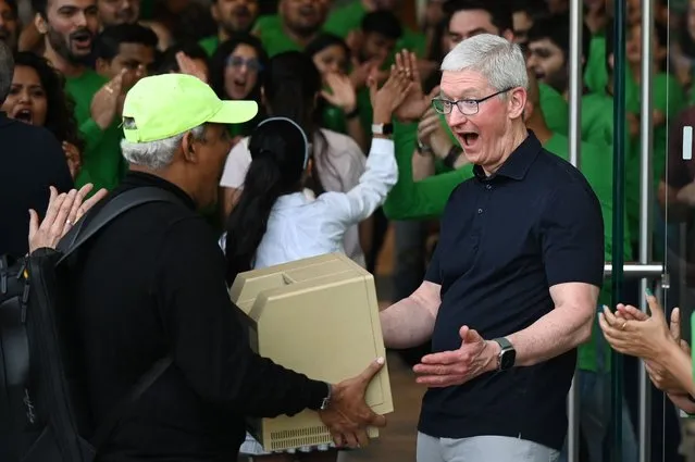 Chief Executive Officer of Apple Tim Cook (R) reacts as a man shows him a Macintosh SE computer during the opening of Apple's first retail store in India, in Mumbai on April 18, 2023. Apple opened its first retail store in India on April 18, underscoring the US tech titan's increasing focus on the South Asian nation as a key sales market and alternative manufacturing hub to China. (Photo by Punit Paranjpe/AFP Photo)