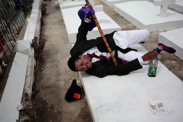A voodoo believer, dressed as “Gede”, a spirit of voodoo, throws himself on a grave during celebrations at the cemetery of Port-au-Prince, Haiti, November 1, 2016. (Photo by Andres Martinez Casares/Reuters)