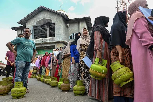 People queue with gas cylinders to buy subsidised Liquefied Petroleum Gas (LPG) for cooking at a distribution centre in Lambaro, Indonesia's Aceh province on May 2, 2023. (Photo by Chaideer Mahyuddin/AFP Photo)