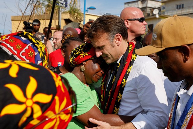 France's president Emmanuel Macron embraces a woman as he speaks with local residents during his visit at the kavani district in Mamoudzou, on the French Indian Ocean territory of Mayotte on December 19, 2024,  following the cyclone Chido's passage over the archipelago. President Emmanuel Macron vowed on December 19 to rebuild the French island territory of Mayotte during his visit after widespread destruction brought on by a cyclone. (Photo by Ludovic Marin/Pool via AFP Photo)
