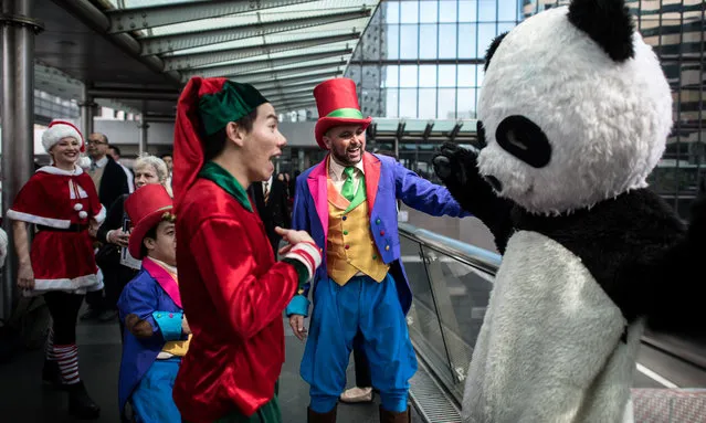 Performers (L) meet a man dressed in a panda costume as they parade in Hong Kong on December 15, 2015 to promote a funfair and festival taking place during the Christmas festive season. Christmas is celebrated worldwide on December 25. (Photo by Philippe Lope/AFP Photo)