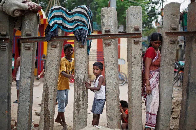 Children play as a woman crosses a railway fence at a slum area in New Delhi, India, July 11, 2018. (Photo by Adnan Abidi/Reuters)