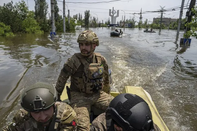 Ukrainian servicemen ride on a speedboat in a flooded neighborhood in Kherson, Ukraine, Thursday, June 8, 2023. Many small boats carrying volunteers and Ukrainian soldiers have shuttled across from Ukrainian-held areas on the west bank to rescue desperate civilians stuck on rooftops, in attics and in other areas amid the deluge. (Photo by Evgeniy Maloletka/AP Photo)