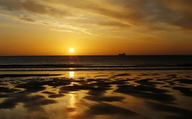 A ship passes across the horizon of  the North Sea near Tynemouth beach, North Tyneside, England at sunrise Tuesday April 19, 2016. (Photo by Owen Humphreys/PA via AP Photo)