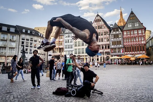 A street artist from Venezuela performs a somersault at the Roemerberg square in Frankfurt in Frankfurt, Germany, Thursday, July 6, 2023. (Photo by Michael Probst/AP Photo)