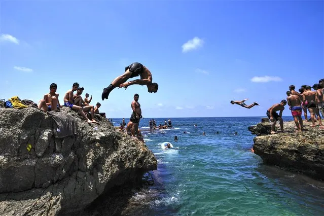 People jump in the water to cool off on a sweltering hot day in the Mediterranean Sea in Beirut, Lebanon, Sunday, July 16, 2023. Were forecast to reach as high as 40 degrees Celsius, 104 Fahrenheit, in some parts of Lebanon. (Photo by Hassan Ammar/AP Photo)