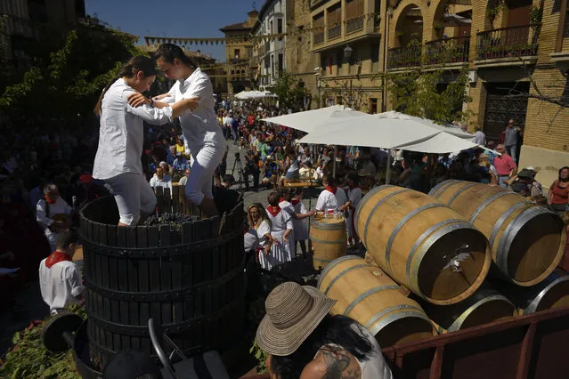 Two teenagers tread the grapes in a oak barrel, during the Wine Harvest Festival, in Olite, northern Spain, Sunday September 2, 2018. This festival marks the beginning of the harvest to produce the new season's wine. (Photo by Alvaro Barrientos/AP Photo)