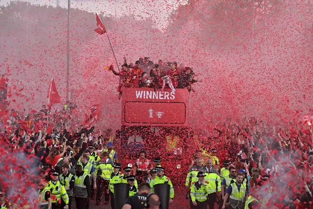Liverpool's players wave from an open-top bus during a parade through the streets of Liverpool in north-west England on May 29, 2022, to celebrate winning the 2021-22 League Cup and FA Cup. Despite the disappointment of losing to real Madrid in the final of the UEAF Champions League, Klopp has called on Liverpool fans to take to the streets of the city on Sunday when they parade the League Cup and FA Cup. (Photo by Oli Scarff/AFP Photo)