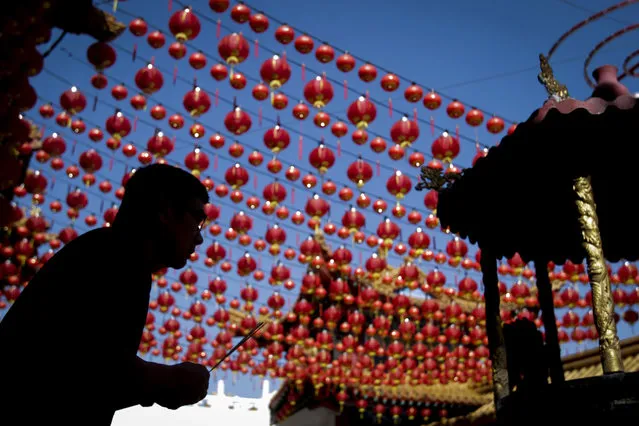 A praying man is silhouetted against traditional Chinese lantern decorations at a temple ahead of the Chinese Lunar New Year in Kuala Lumpur, Malaysia, on Tuesday, February 17, 2015. (Photo by Joshua Paul/AP Photo)