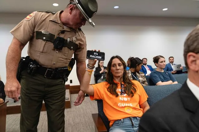 A person displaying a sign on a phone is instructed by State Troopers to leave a House Subcommittee meeting on the second day of a special session to discuss gun violence in the wake of the Covenant School shooting in Nashville, Tennessee, U.S., August 22, 2023. (Photo by Cheney Orr/Reuters)
