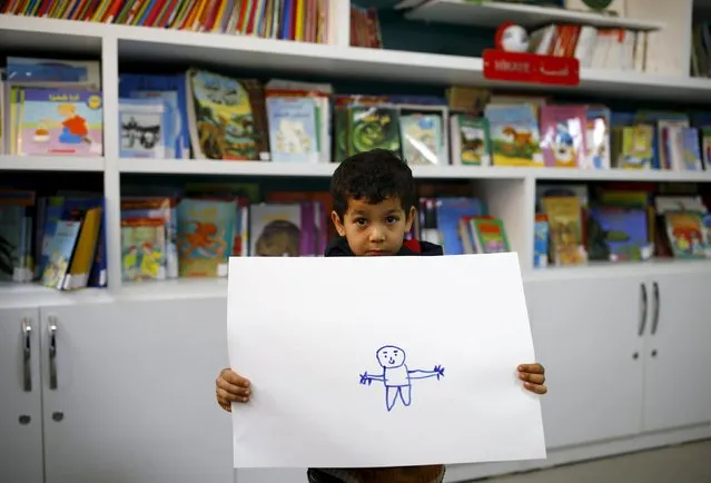 Syrian refugee boy Gays Cardak, 6, shows his drawing in a school library in the Yayladagi refugee camp in Hatay province near the Turkish-Syrian border, Turkey, December 16, 2015. "I'm going to be a doctor and an engineer. We the engineers will rebuild Syria, and I'll take the (soldiers) to hospital", Cardak said. (Photo by Umit Bektas/Reuters)