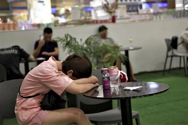 A person rests on a table at a shopping mall to take refuge from the heat during a power outage in Hanoi, Vietnam on Saturday, June 10, 2023. Power outages are leaving Vietnamese homes and businesses without power for hours at a time, as a prolonged drought and high temperatures strain the fast-growing economy's capacity to keep up. (Photo by Hau Dinh/AP Photo)