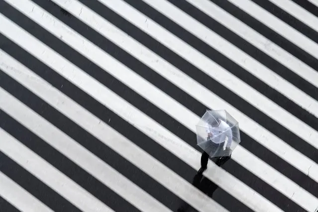 A pedestrian crosses a street on a rainy day in Tokyo on May 13, 2021. (Photo by Charly Triballeau/AFP Photo)