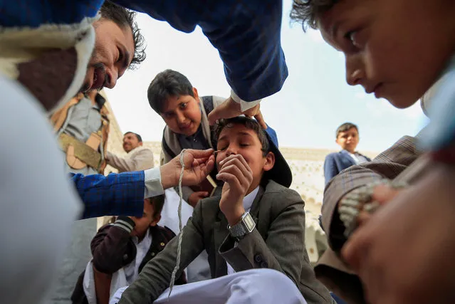 A Yemeni man applies traditional Kohl eyeliner to a youth's eyelid at the Mosque of Sanaa during the Muslim fasting month of Ramadan, on April 16, 2021. (Photo by Mohammed Huwais/AFP Photo)
