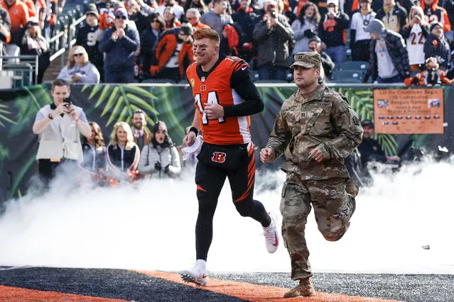 Cincinnati Bengals quarterback Andy Dalton (14) runs onto the field with a member of the armed forces before an NFL football game against the New Orleans Saints, Sunday, November 11, 2018, in Cincinnati. (Photo by Frank Victores/AP Photo)