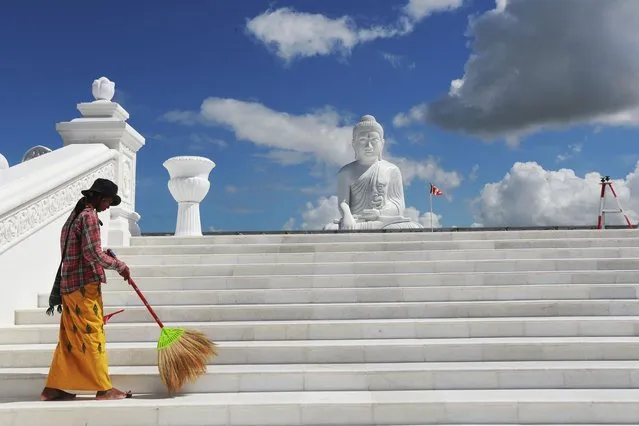 A laborer sweeps near the sitting Maravijaya Buddha statue made with marble rock, Friday, July 21, 2023, in Naypyitaw, Myanmar. (Photo by Aung Shine Oo/AP Photo)