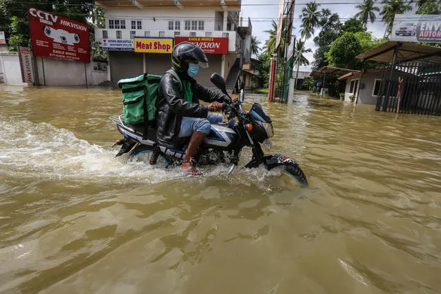 A Sri Lankan food delivery man rides his motorbike through a submerged road after heavy rainfall in Biyagama suburb of Colombo, Sri Lanka, 06 June 2021. (Photo by Chamila Karunarathne/EPA/EFE)
