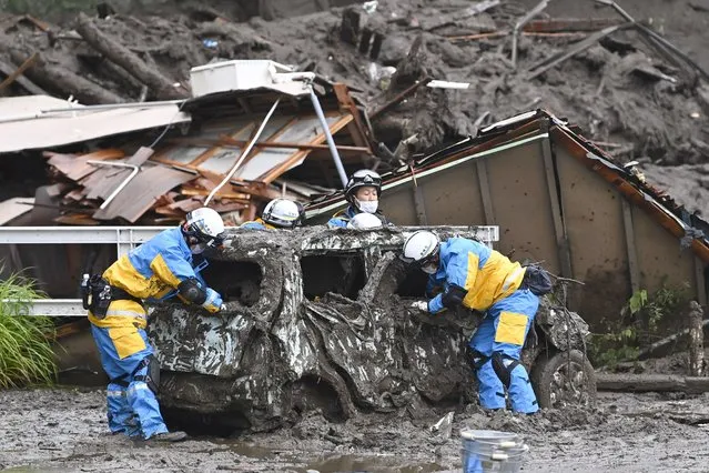 Rescuers check a damaged vehicle at the site of a mudslide in Atami, Shizuoka prefecture, southwest of Tokyo, Sunday, July 4, 2021. A gush of mud swept away homes and cars in the resort town. (Photo by Kyodo News via AP Photo)