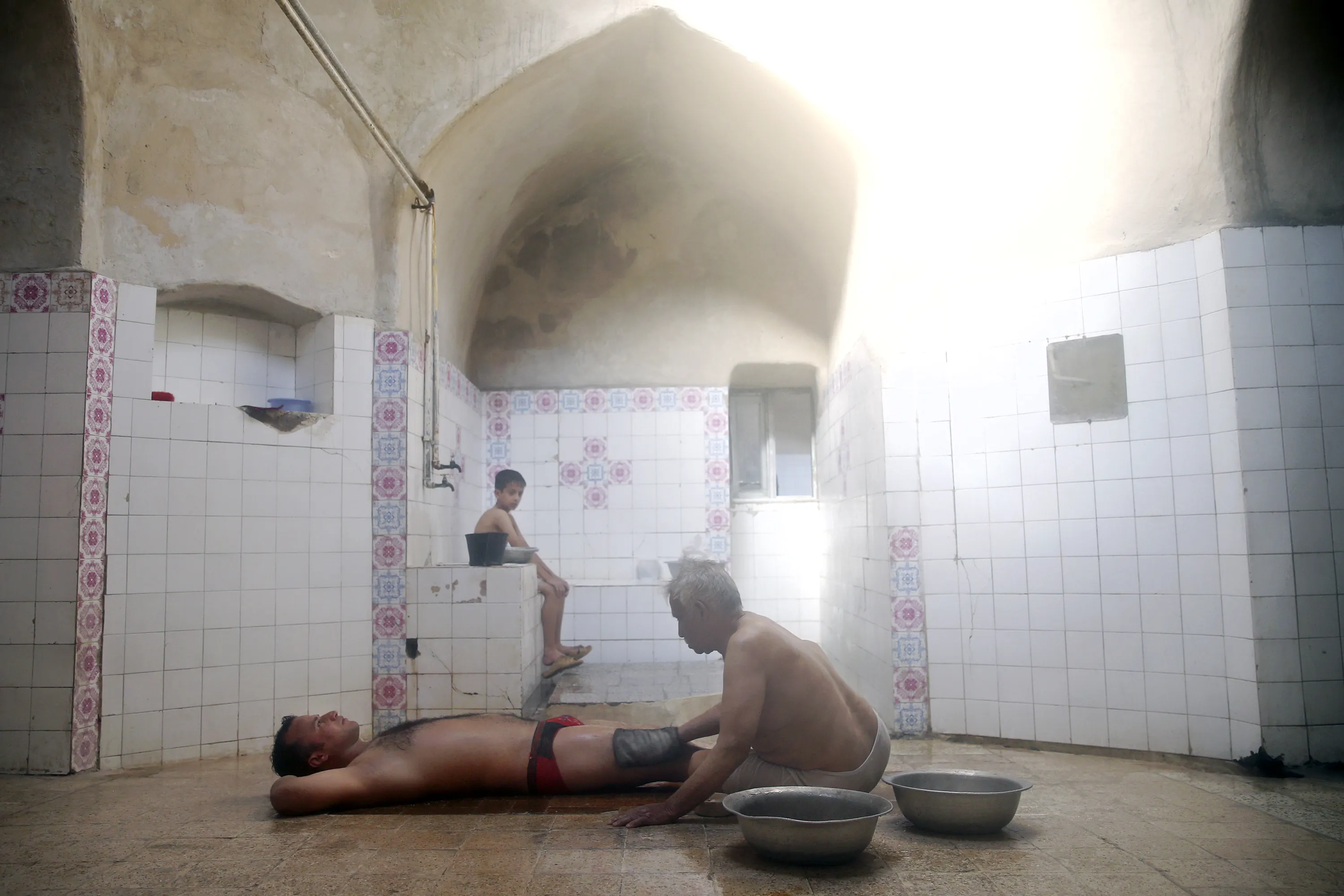 bathhouse worker Ali Tayyeb, 70, scrubs a man to remove dead skin after sit...