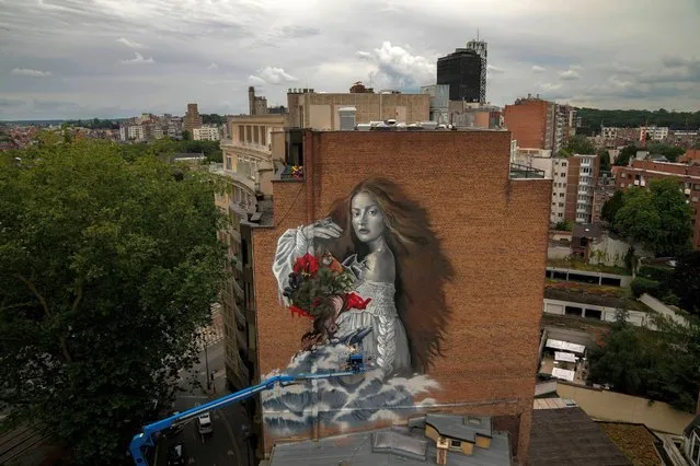 Spanish street artist Lula Goce works in a giant mural in Brussels, Monday, July 12, 2021. The mural of “mother nature” is part of a world wide project by Street Art for Mankind NGO pursuing to raise awareness on ecosystem restoration and climate change. (Photo by Francisco Seco/AP Photo)