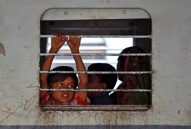 A girl looks out from inside a coach of a stationed passenger train at a railway station in Ahmedabad, India, February 25, 2016. (Photo by Amit Dave/Reuters)